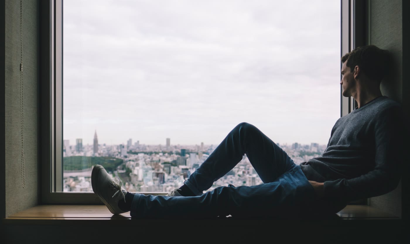 Homme assis devant une fenêtre qui regarde la ville